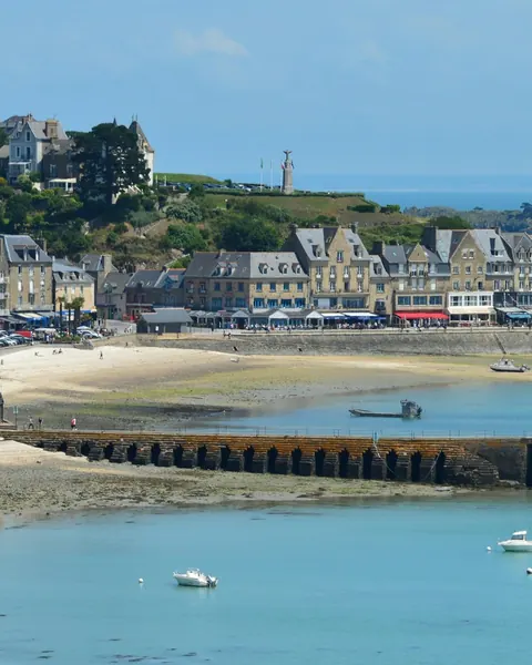 Le port et ses maisons alignées au-dessus de la plage, la jetée et des bateaux au mouillage